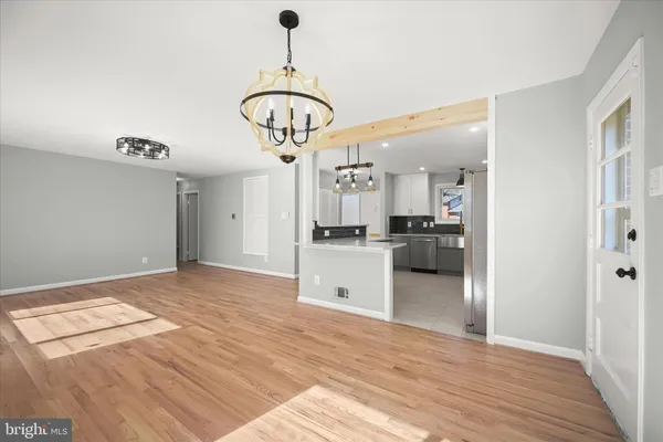 a view of an empty room with wooden floor and a ceiling fan