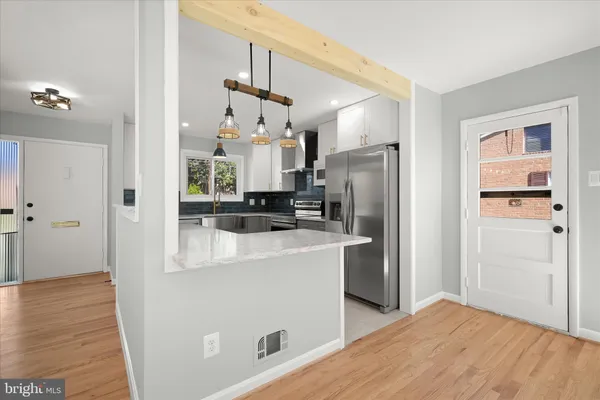 a view of an empty room with wooden floor and a ceiling fan