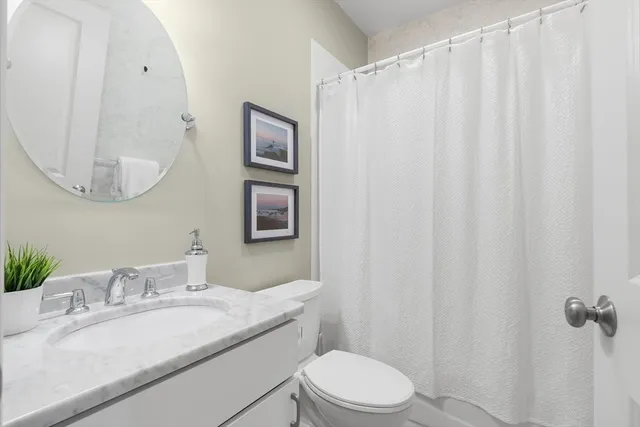 a bathroom with a granite countertop sink vanity mirror and toilet