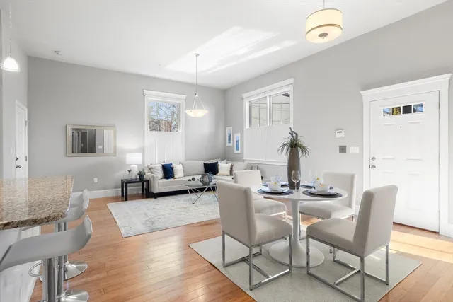 a kitchen with granite countertop a stove a sink dishwasher a refrigerator and a dining table with wooden floor