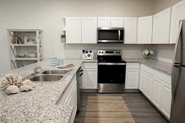 802 South 5th Street, Unit 1 Bonham, TX 75418 - Photo 11 of 25 Kitchen featuring white shaker cabinetry, stainless steel appliances, speckled stone countertops, a subway tile backsplash, and dark wood-finish flooring