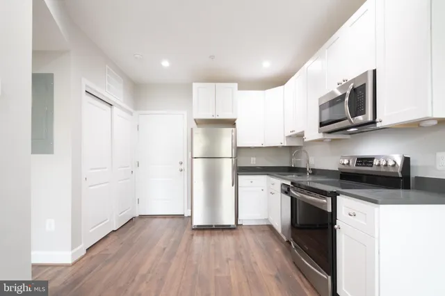 a kitchen with stainless steel appliances granite countertop a stove top oven a refrigerator a sink and dishwasher with wooden floor