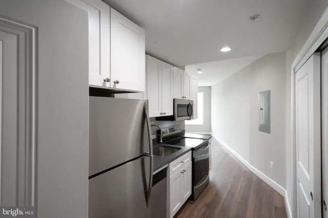 a kitchen with stainless steel appliances a refrigerator a sink and white cabinets