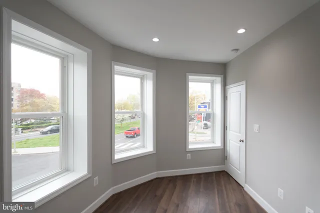 a view of an empty room with a window and wooden floor