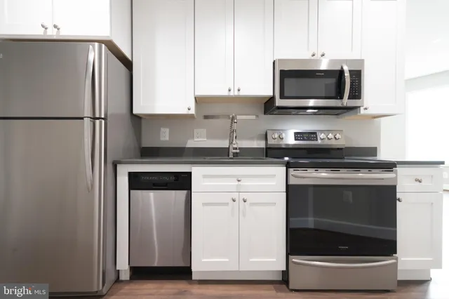 a kitchen with stainless steel appliances a stove microwave and sink