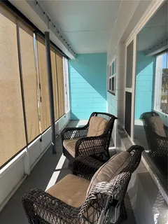 a balcony with two chairs and a potted plant