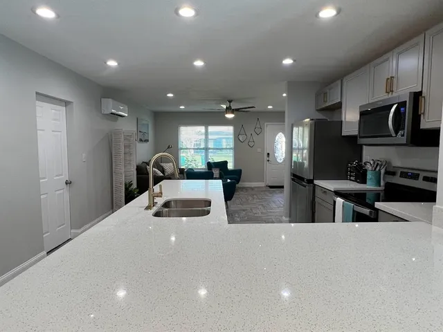 a kitchen with stainless steel appliances kitchen island granite countertop a refrigerator and a sink