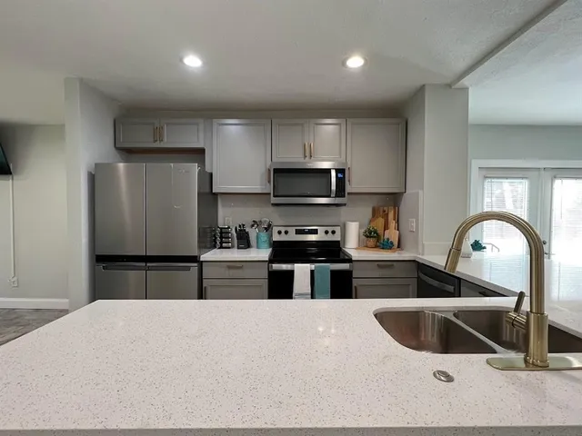 a kitchen with granite countertop a refrigerator and a sink