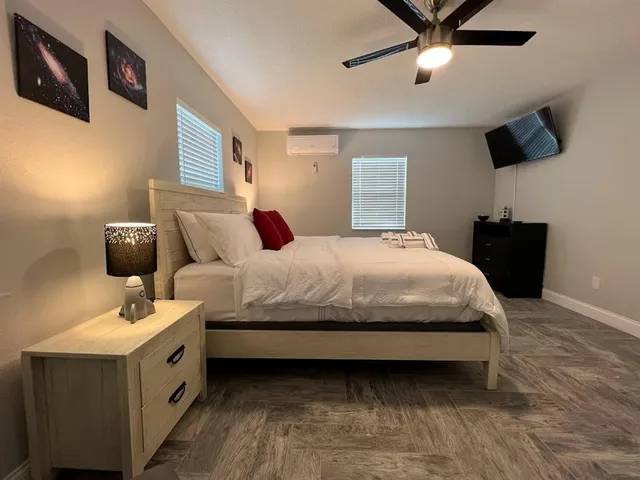 a bedroom with a bed and a flat tv screen on the dresser