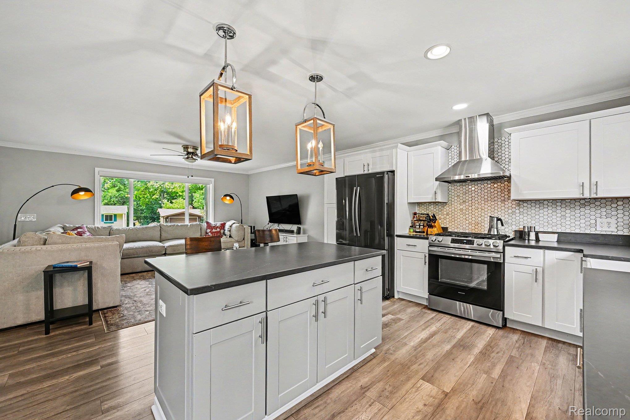 2104 Highfield Road Waterford, MI 48329 - Photo 9 of 38 Open concept kitchen featuring an island with cabinet storage, white shaker-style cabinetry, and quartz countertops