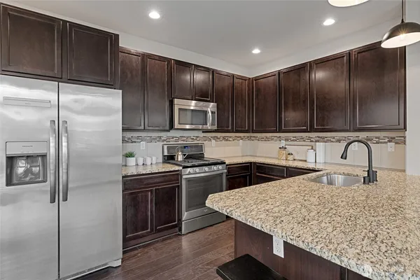 a kitchen with stainless steel appliances granite countertop a sink a stove a refrigerator with a dining table and chairs