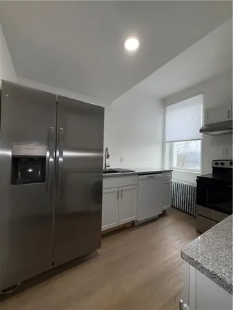 a kitchen with stainless steel appliances granite countertop a refrigerator a sink and wooden cabinets