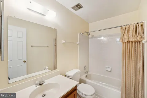 a bathroom with a tub shower sink vanity and a toilet