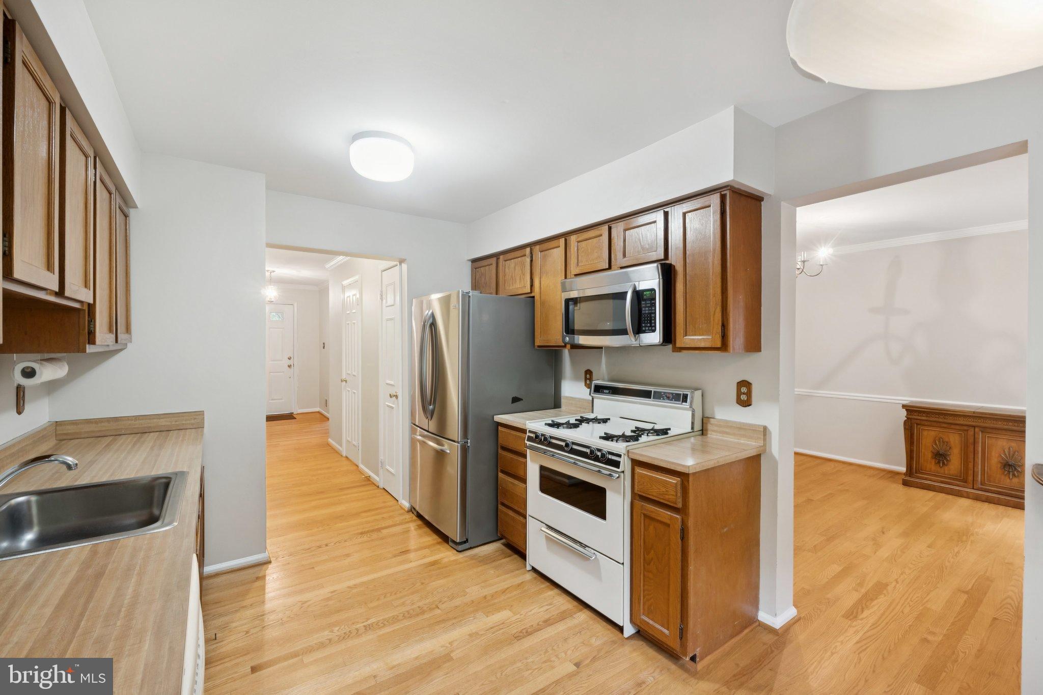 7904 Jensen Place Bethesda, MD 20817 - Photo 9 of 22 a kitchen with stainless steel appliances a stove a sink a refrigerator white cabinets and wooden floor