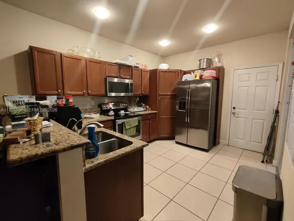 a kitchen with stainless steel appliances a refrigerator a sink a stove a microwave and wooden cabinets