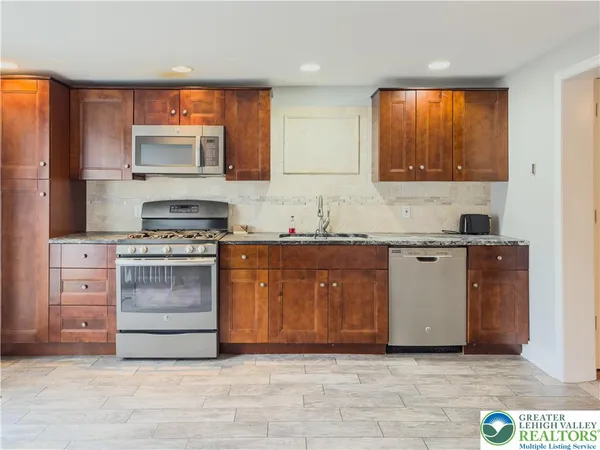 a kitchen with stainless steel appliances granite countertop a stove a sink and a refrigerator