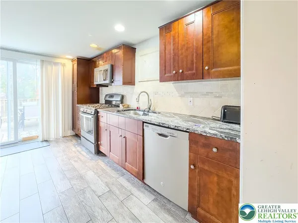 a kitchen with stainless steel appliances granite countertop a stove a sink and a refrigerator with wooden floor
