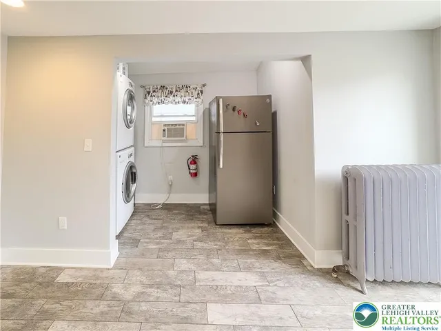 a view of a refrigerator in kitchen and an empty room