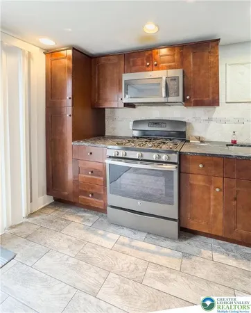 a kitchen with stainless steel appliances granite countertop a stove a sink and a microwave