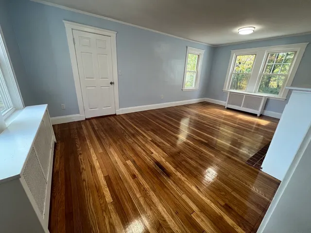 a view of an empty room with wooden floor and window