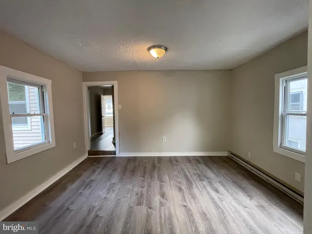 an empty room with wooden floor and windows