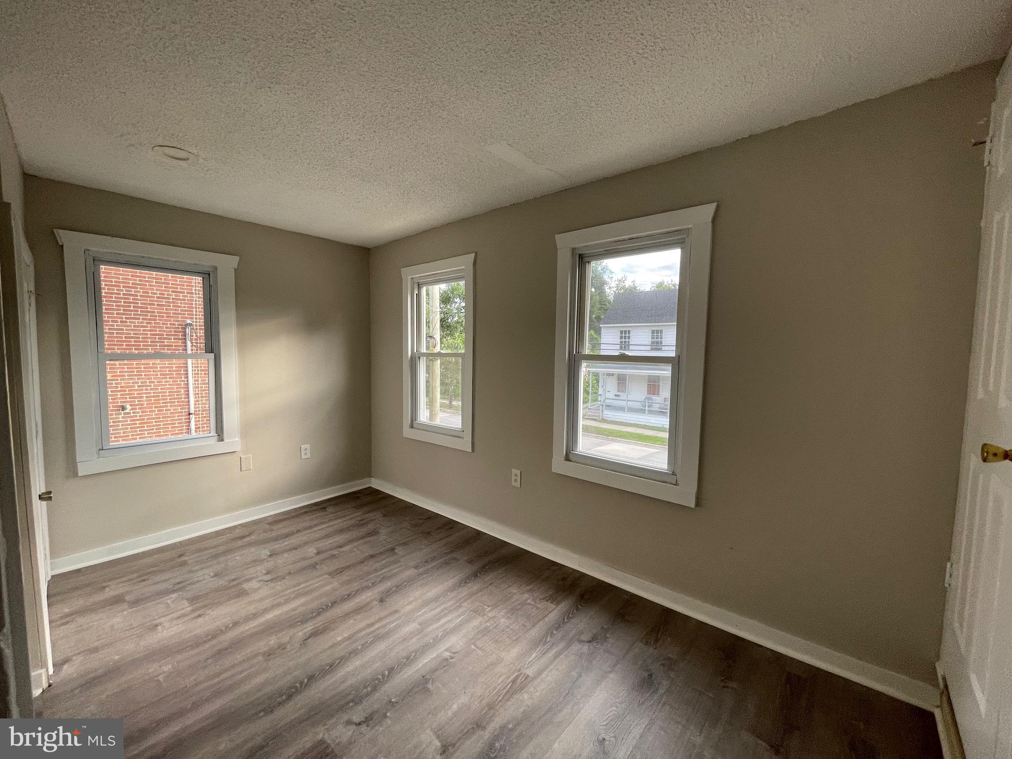 382 East Broadway, Unit 2 Salem, NJ 08079 - Photo 4 of 6 a view of an empty room with wooden floor and a window