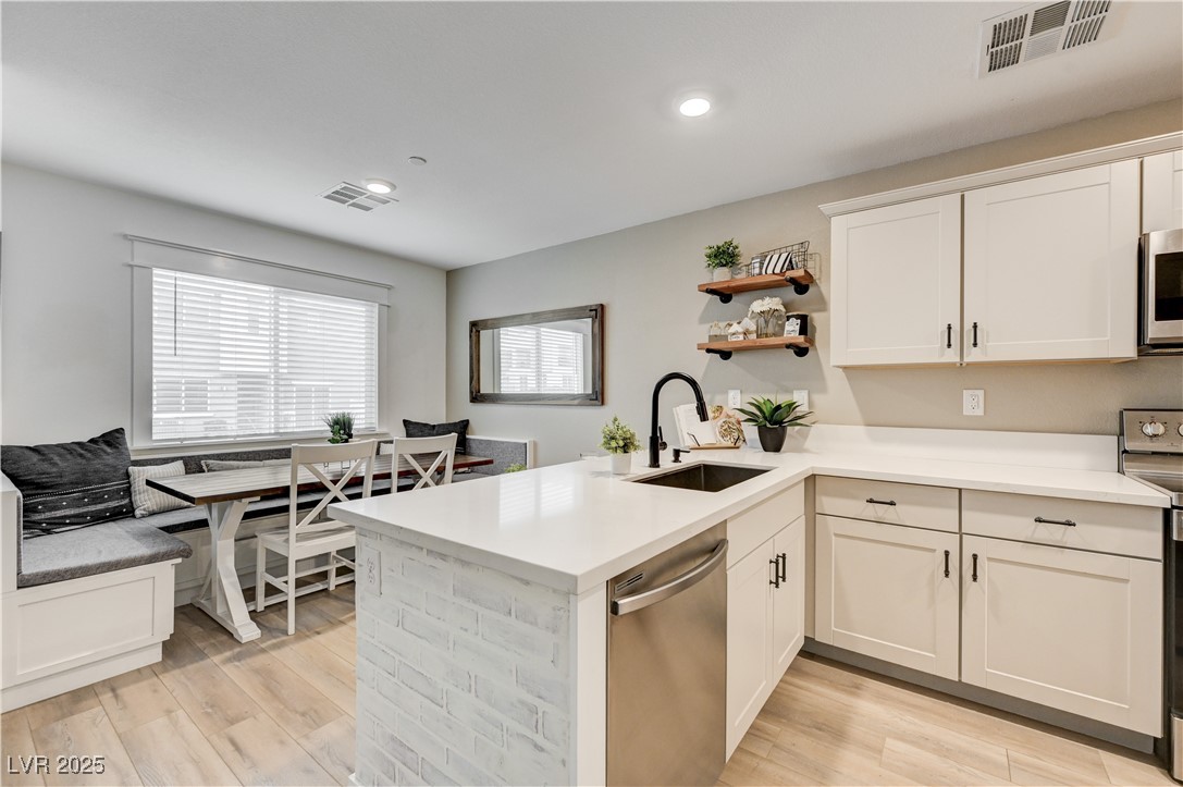 12106 Azure Gate Road, Unit 3 Las Vegas, NV 89183 - Photo 11 of 77 Kitchen featuring open shelves, stainless steel appliances, a peninsula, white cabinets, and light wood-style floors