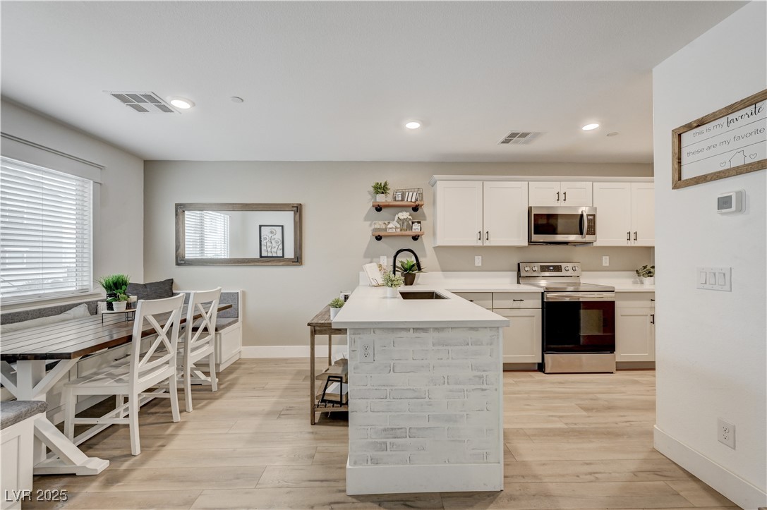 12106 Azure Gate Road, Unit 3 Las Vegas, NV 89183 - Photo 12 of 77 Kitchen featuring stainless steel appliances, white cabinets, open shelves, a peninsula, and a breakfast bar area