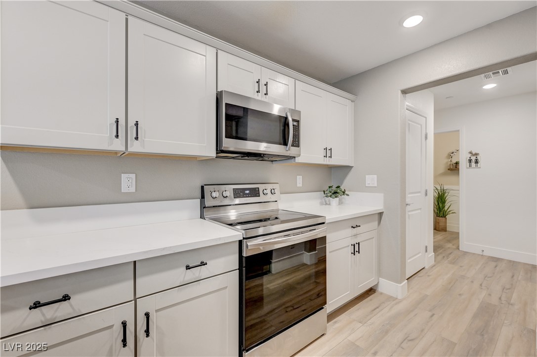 12106 Azure Gate Road, Unit 3 Las Vegas, NV 89183 - Photo 21 of 77 Kitchen with appliances with stainless steel finishes, white cabinetry, light wood-style flooring, and recessed lighting