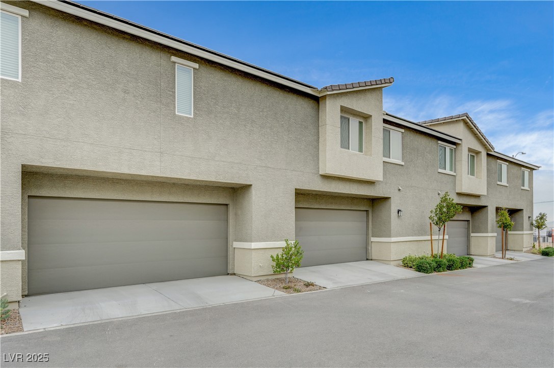 12106 Azure Gate Road, Unit 3 Las Vegas, NV 89183 - Photo 48 of 77 View of front facade featuring stucco siding, a tile roof, driveway, and an attached garage