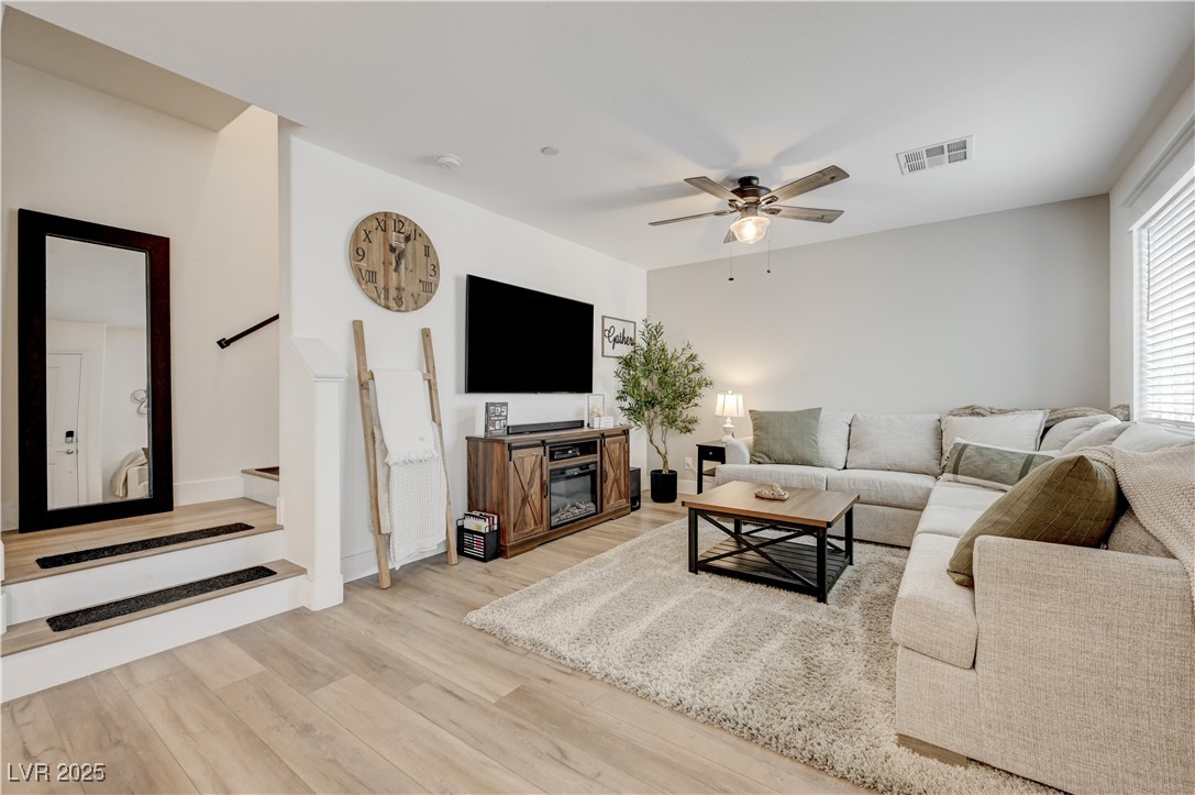 Living room with light wood finished floors and ceiling fan