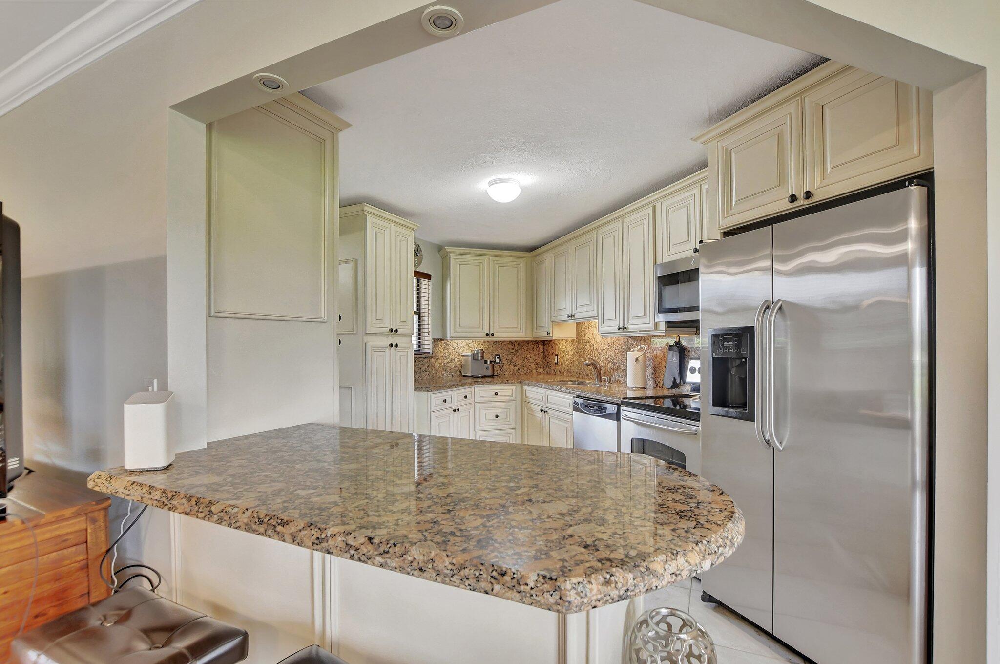 5901 Camino Del Sol, Unit 107 Boca Raton, FL 33433 - Photo 11 of 51 a kitchen with stainless steel appliances granite countertop a sink refrigerator and cabinets