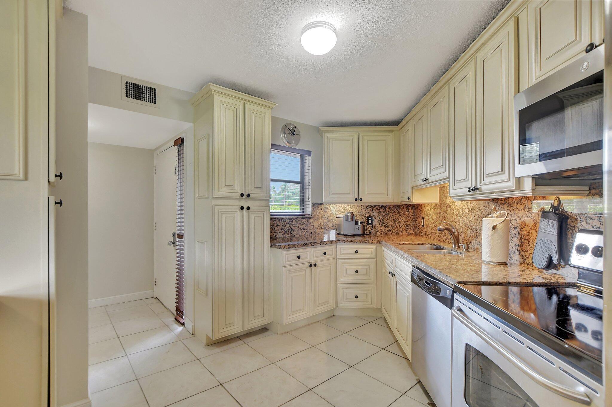 5901 Camino Del Sol, Unit 107 Boca Raton, FL 33433 - Photo 12 of 51 a kitchen with stainless steel appliances a stove sink and cabinets