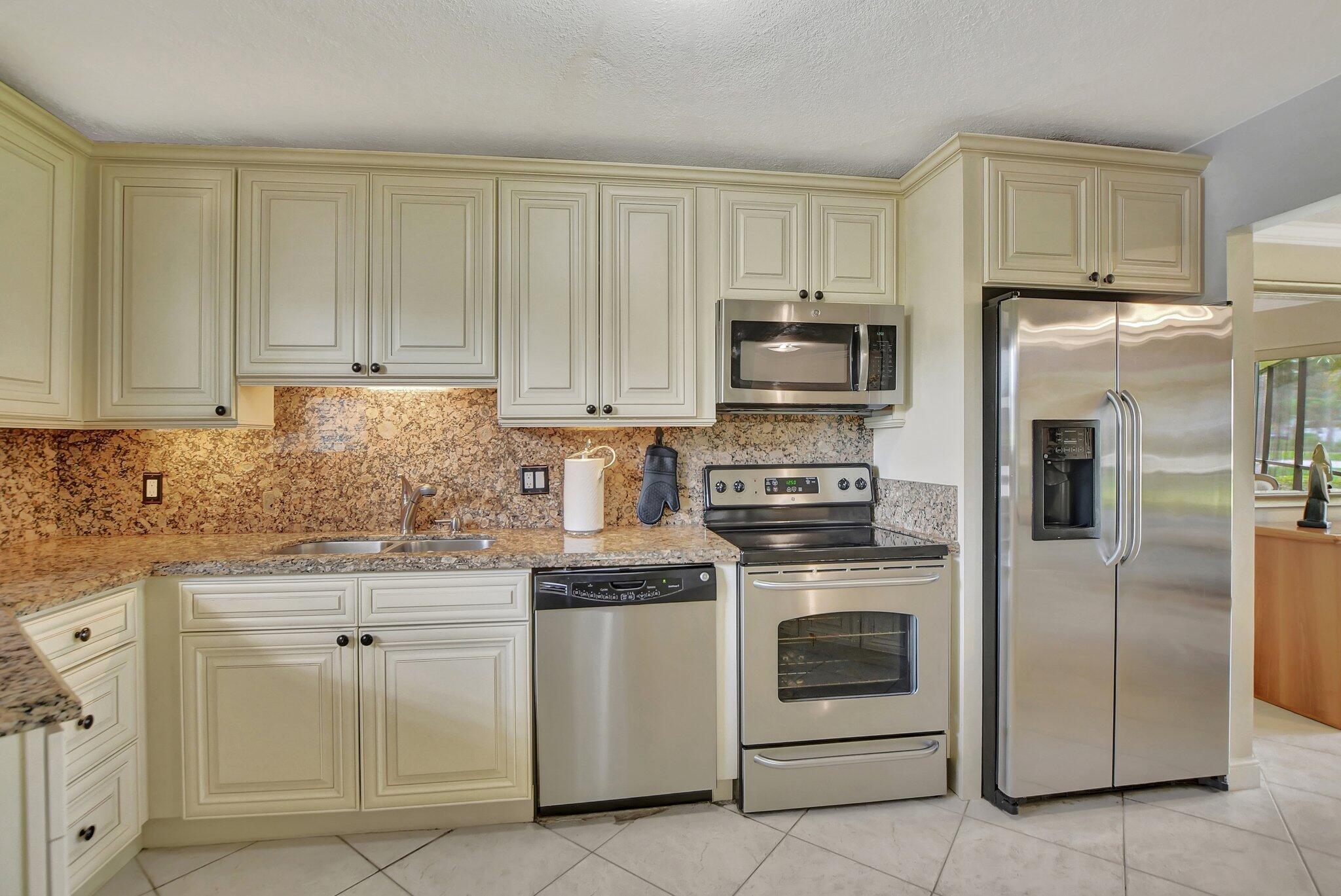 5901 Camino Del Sol, Unit 107 Boca Raton, FL 33433 - Photo 13 of 51 a kitchen with white cabinets and stainless steel appliances