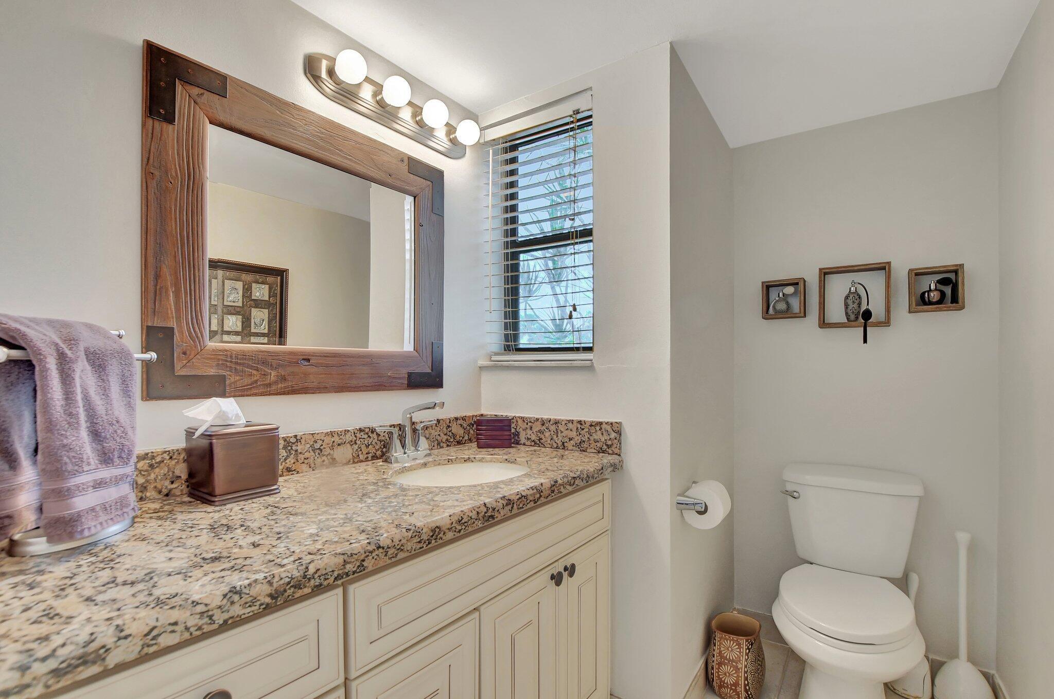 5901 Camino Del Sol, Unit 107 Boca Raton, FL 33433 - Photo 22 of 51 a bathroom with a granite countertop sink mirror and toilet