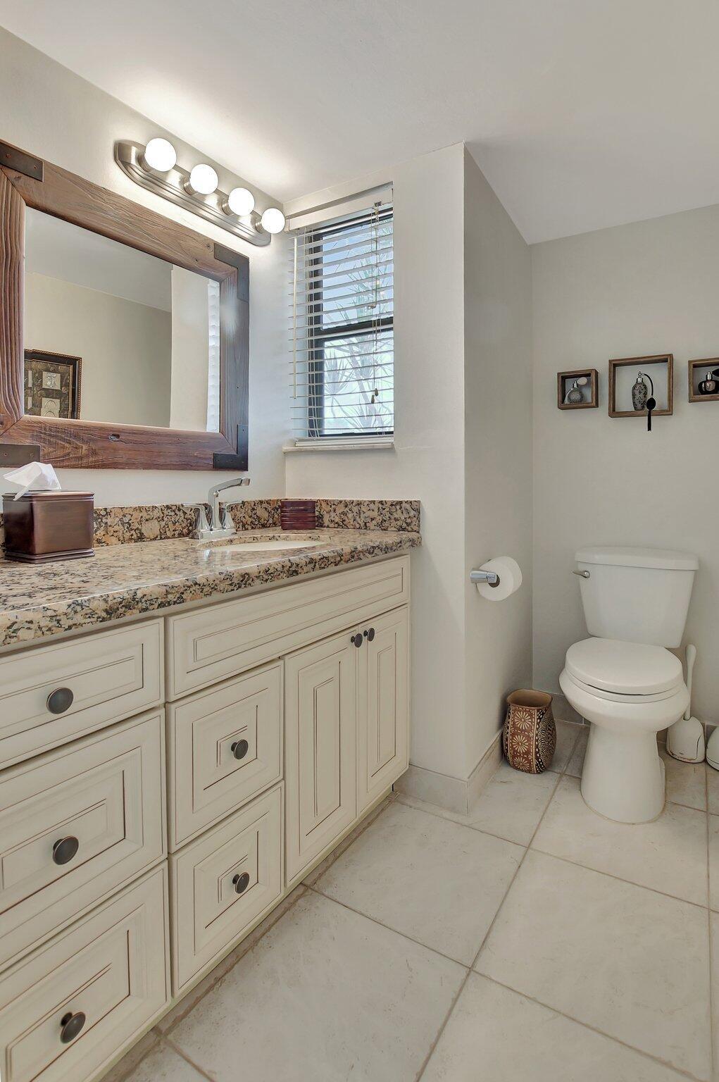5901 Camino Del Sol, Unit 107 Boca Raton, FL 33433 - Photo 23 of 51 a spacious bathroom with a granite countertop toilet sink and mirror