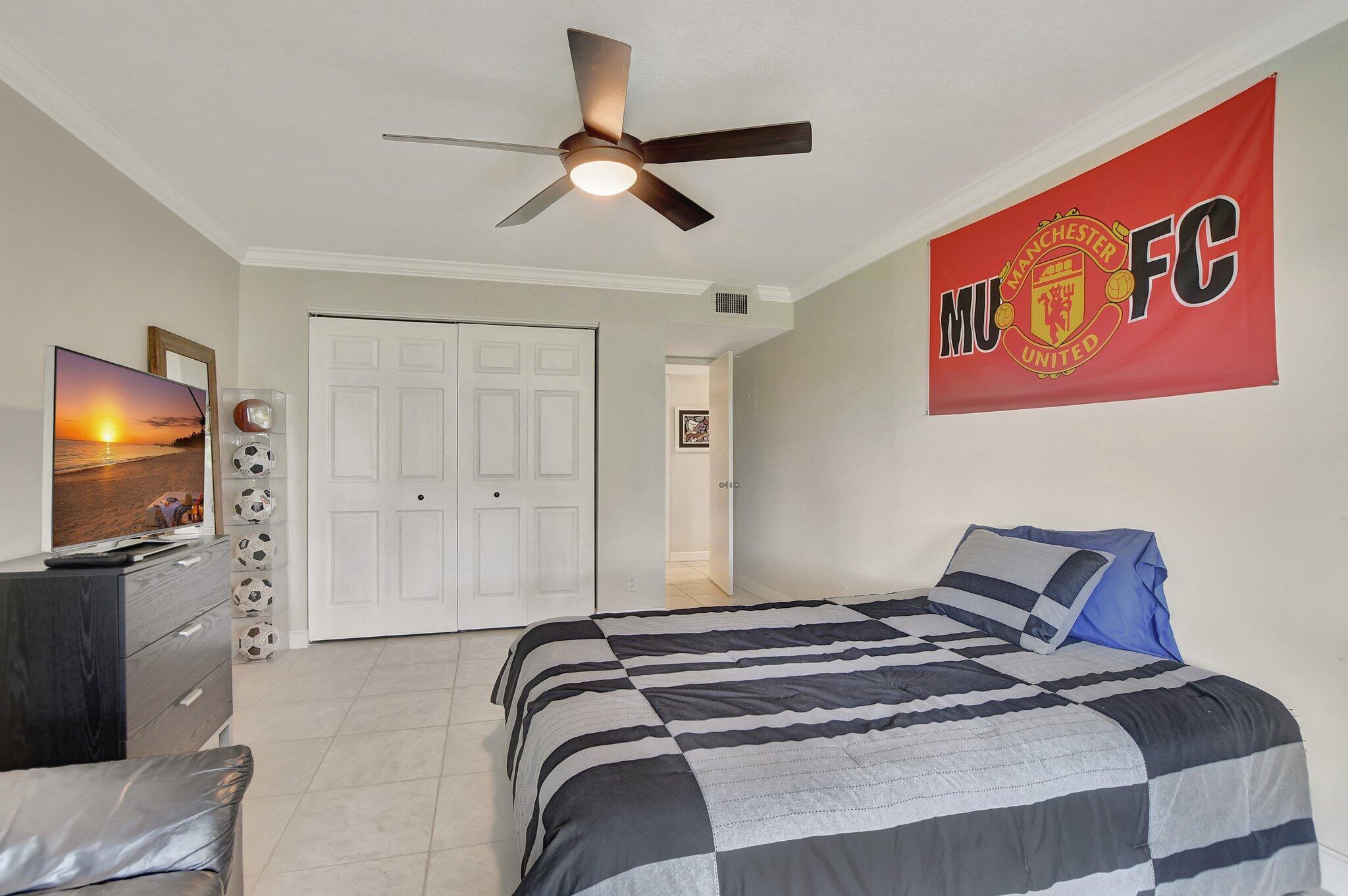 5901 Camino Del Sol, Unit 107 Boca Raton, FL 33433 - Photo 26 of 51 a bedroom with a bed and a flat screen tv