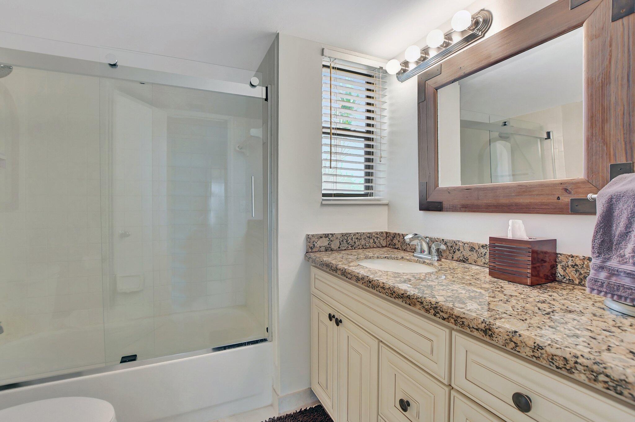 5901 Camino Del Sol, Unit 107 Boca Raton, FL 33433 - Photo 27 of 51 a bathroom with a granite countertop sink a mirror and a shower