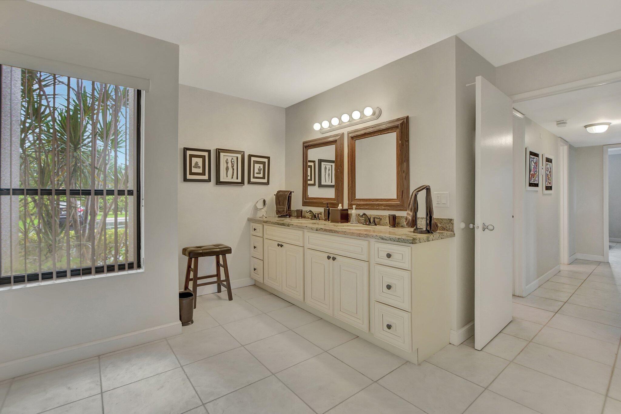 5901 Camino Del Sol, Unit 107 Boca Raton, FL 33433 - Photo 31 of 51 a spacious bathroom with a granite countertop sink a mirror a bathtub and next to a window