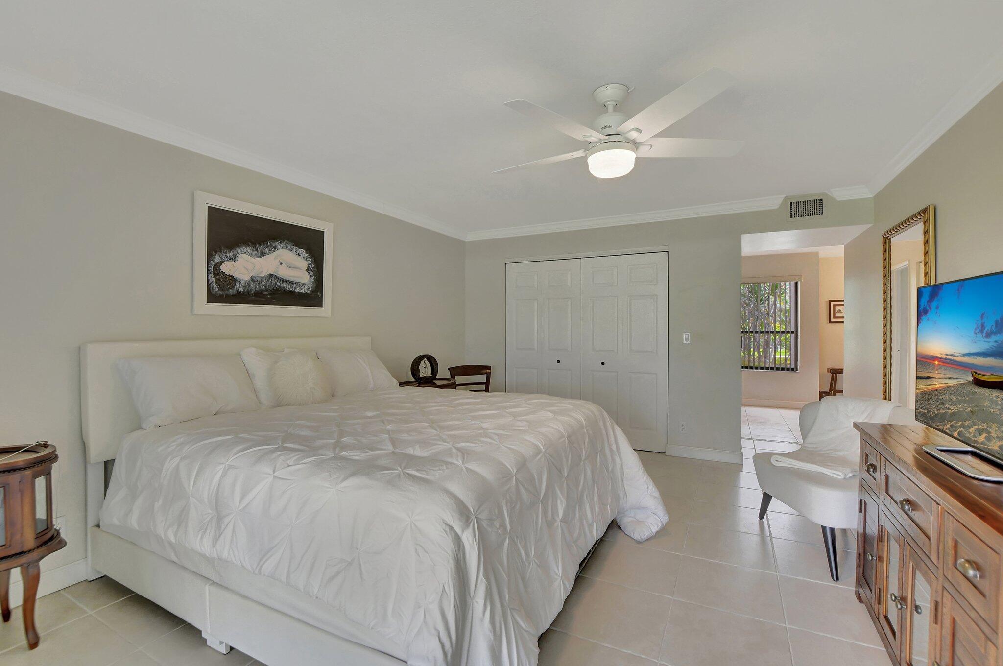 5901 Camino Del Sol, Unit 107 Boca Raton, FL 33433 - Photo 36 of 51 a bedroom with a bed and a chandelier