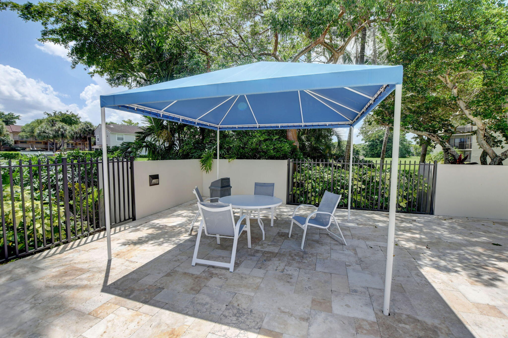 5901 Camino Del Sol, Unit 107 Boca Raton, FL 33433 - Photo 48 of 51 a view of a patio with a table and chairs under an umbrella