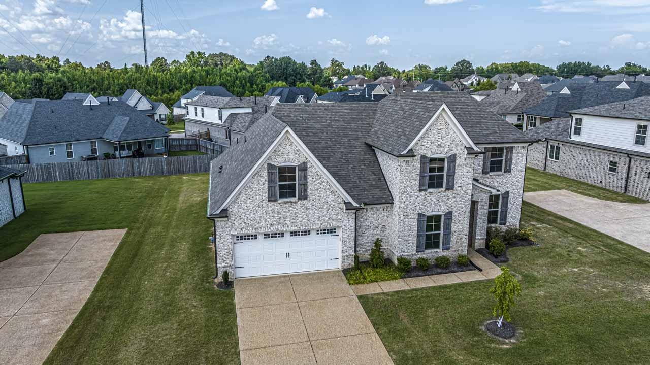 View of front of house featuring stone siding, a residential view, driveway, and a garage