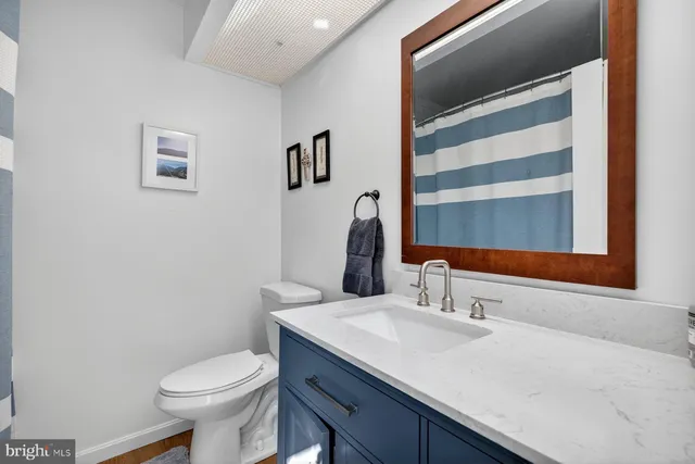a bathroom with a granite countertop sink and a toilet