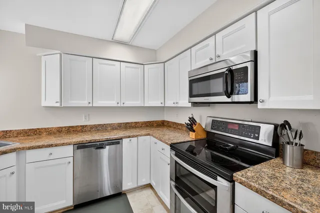 a kitchen with granite countertop white cabinets and stainless steel appliances