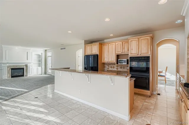 a large kitchen with kitchen island granite countertop a stove top oven a sink a counter space and cabinets