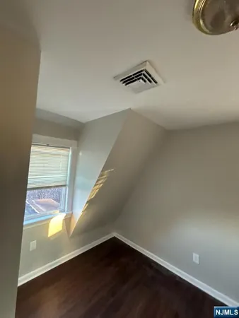 a view of an empty room with wooden floor and windows