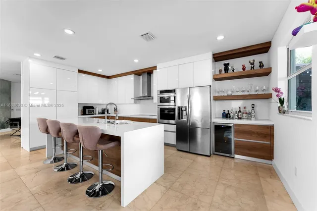 a kitchen with stainless steel appliances kitchen island granite countertop a refrigerator and a stove top oven