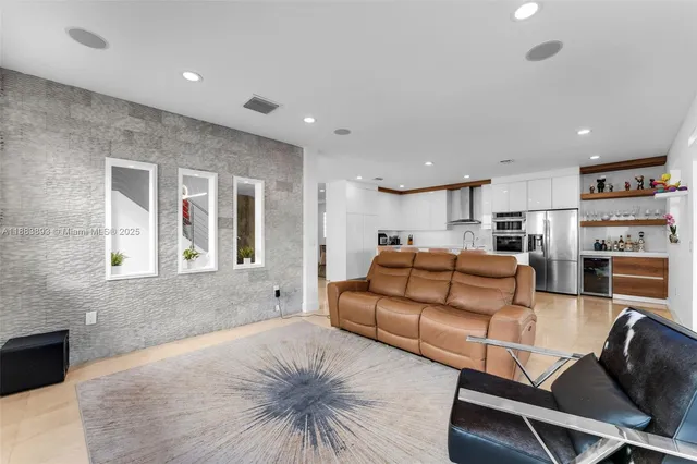 a living room with furniture kitchen view and a window
