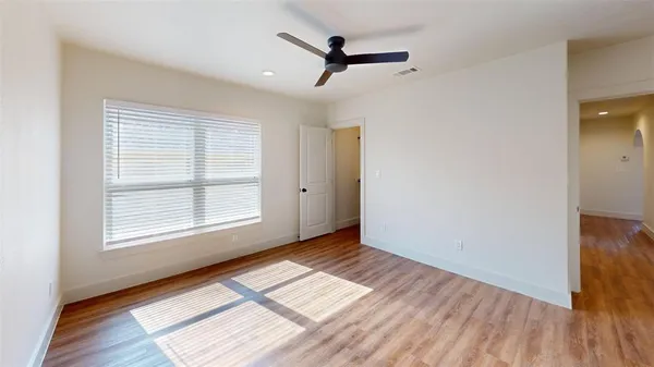 a view of empty room with wooden floor and fan
