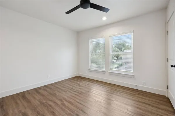 an empty room with wooden floor fan and windows